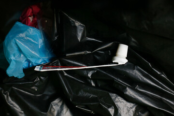 Empty toothpaste tube on plastic trash bag