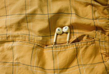 white earphones hanging out on side pocket pants