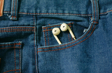 white earphones hanging out on side pocket of denim pants