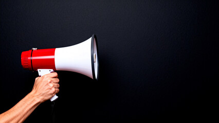 Red and white megaphone against black wall
