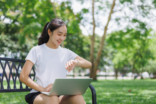 Young woman checking smartwatch while working outdoors - Powered by Adobe