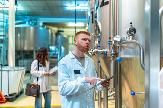 Man and woman inspecting beer fermentation tanks