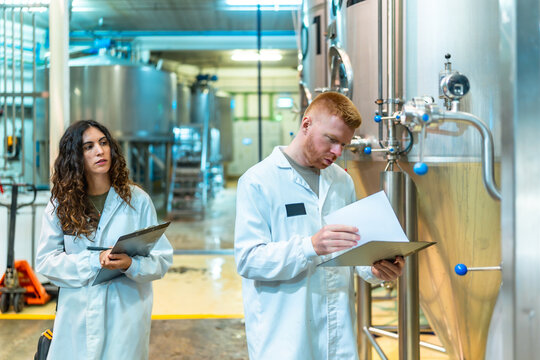 Workers inspecting brewing process and quality in beer factory