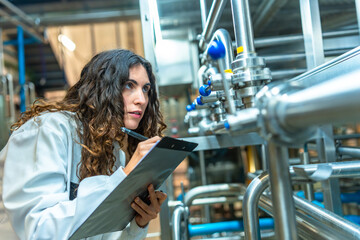 Woman inspecting industrial pipes in a food factory