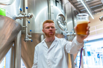 Man in lab coat checking beer quality in brewery