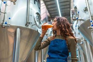 Woman tasting craft beer for quality control in brewery