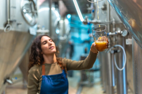 Woman brewer pouring craft beer during quality check