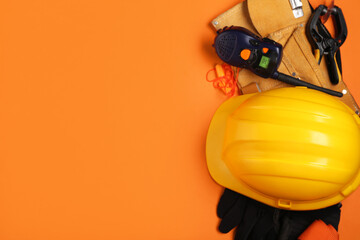 Hardhat, radio transceiver and safety equipment on orange background
