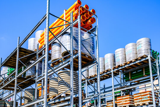 Bright and organized construction supplies stored on shelves under clear blue sky at a busy logistics facility