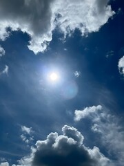 Beautiful view of a bright sunny sky with dramatic clouds surrounding the shining sun.