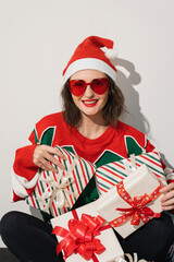 Christmas model wearing red sunglasses and Santa hat with striped gifts
