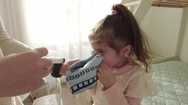 Mother using syringe filled with saline water for washing her nasal's daughter.