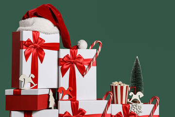 Beautiful gift boxes with candy canes, Christmas decorations, cup of cacao and Santa hat on green...