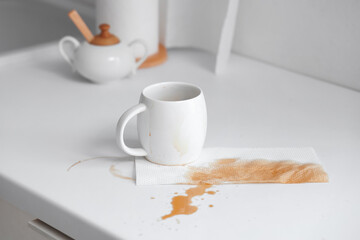 Cup and paper towel with coffee stains on table in kitchen