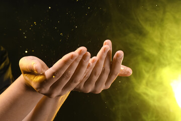 Female hands with energy sparkles and yellow light on black background