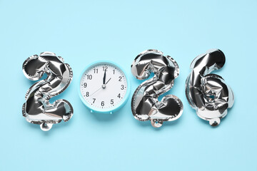 Figure 2026 made of foil balloons with alarm clock on blue background
