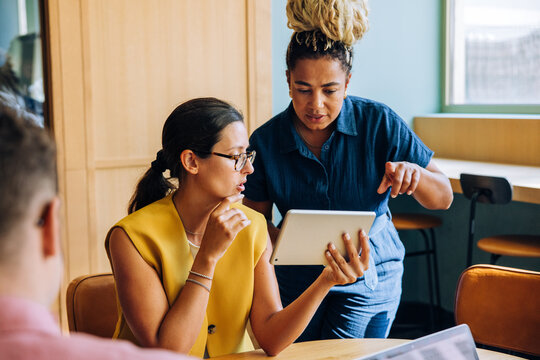 Fototapeta Two businesswomen discussing ideas using a digital tablet during a meeting