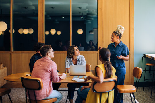 Diverse group of colleagues discussing ideas around a small conference table - Powered by Adobe