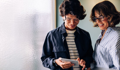 Two cheerful professionals using a tablet device