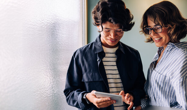 Two cheerful professionals using a tablet device - Powered by Adobe