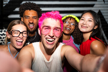 Multiethnic group of young friends having fun on the streets in the night - Stylish cool multiracial people wearing stylish clothing hanging out before party in a disco club
