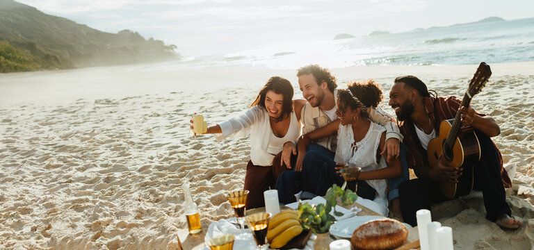 Friends on a sunny beach picnic with guitar - Powered by Adobe