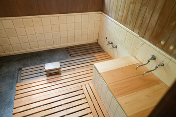 A small bathroom with a wooden floor and a wooden bench. The bench is next to a tub and a sink