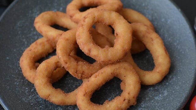 Onion rings or fried squid in breadcrumbs with sauce, takeaway food. Onion rings fried, fast food as a background for your design