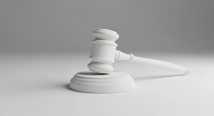 A white gavel resting on its base on a white surface against a white and light gray background