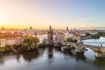 Stunning view of Old Town Bridge Tower at Charles Bridge during sunset. The serene Vltava River reflects the historic architecture of Prague, creating a picturesque scene.