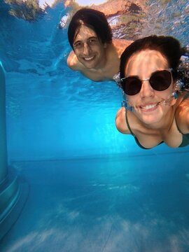 Couple smiling at the camera taking a selfie together underwater