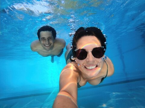 Couple smiling at the camera taking a selfie together underwater