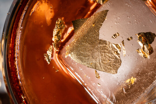 close up of an Ice cube in a red cocktail with edible gold