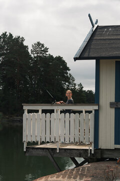 girl fishing by the sea from a traditional Swedish hut