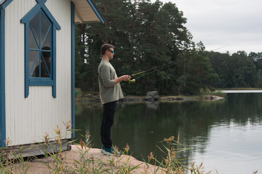 man fishing by the sea and a Swedish cabin