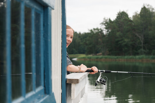 girl happily fishing by the sea at her Swedish cabin