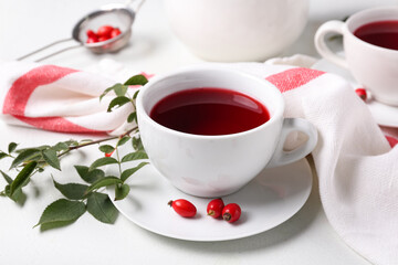 Cup of hot rose hip tea and berries on white background, closeup