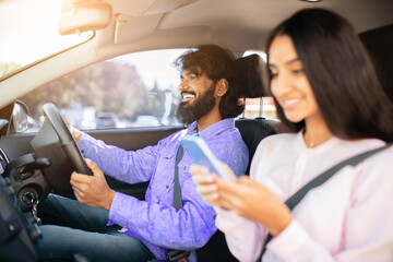 Indian couple driving together, man focused on road while woman uses smartphone. Shows modern lifestyle, tech habits, and connection in shared commute, closeup