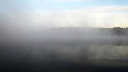 Fototapeta premium early autumn morning by the lake, fog hides the outlines of trees and bushes, blurred background