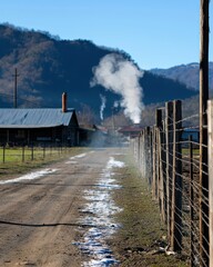 Serene Dusty Road Near Barn with Smoke in Mountain Landscape
