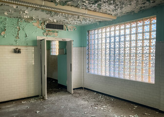 Open door in a decrepit room with peeling paint inside an abandoned and haunted hospital 