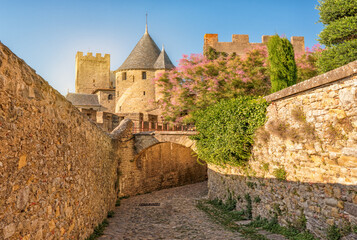 Medieval fortress walls and towers of Carcassonne at sunset, France. Old medieval walls of Carcassonne illuminated by purple sunset sky.