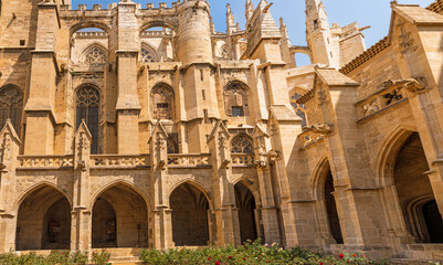 The Gothic cathedral of Narbonne, France, featuring monumental stone walls, arches, and detailed...