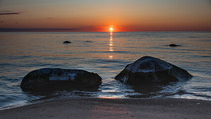 Magical sunset by the sea, the last rays of the sun are reflected in the calm sea surface, bright...