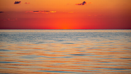 Magical sunset by the sea, the sun has set, the colors of the sunset are reflected in the calm sea...