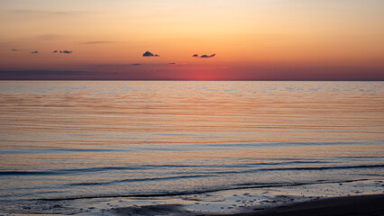 Magical sunset by the sea, the last rays of the sun are reflected in the calm sea surface, bright...