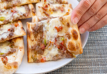 Delicious flatbread topped with ground meat and melted cheese served on a plate at a casual gathering