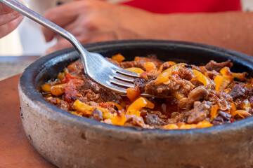 Delicious beef and vegetable dish served in traditional stone plate at outdoor eatery during sunny day