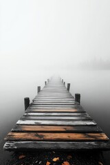 Obraz premium Serene landscape view with a timber pier disappearing into rising mist over a tranquil waterbody