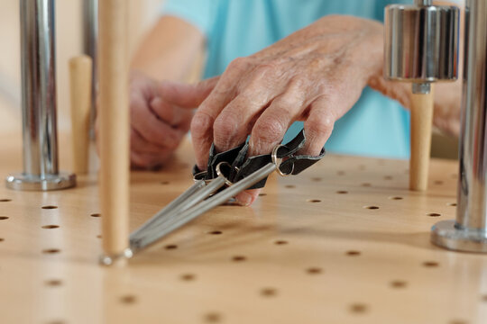Physical activity on motor skills. Hand of anonymous senior woman doing exercises on training equipment in neurological hospital, close-up view - Powered by Adobe